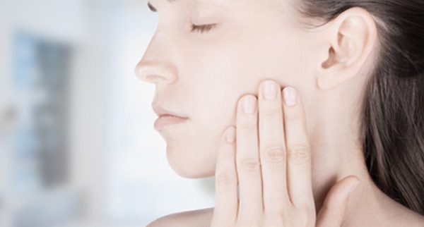 Frau hält sich die Hand an den schmerzenden Kiefer
